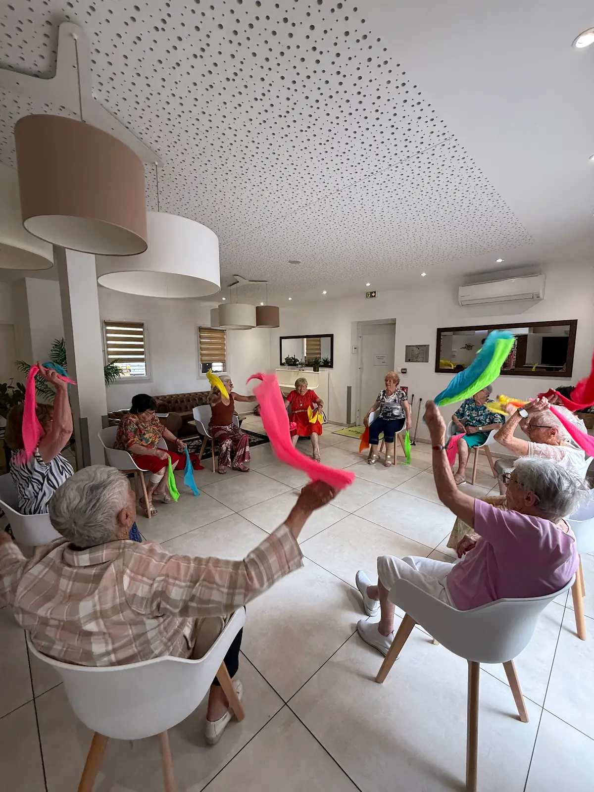 Des résidentes participent ensemble à une séance avec des foulards colorés.